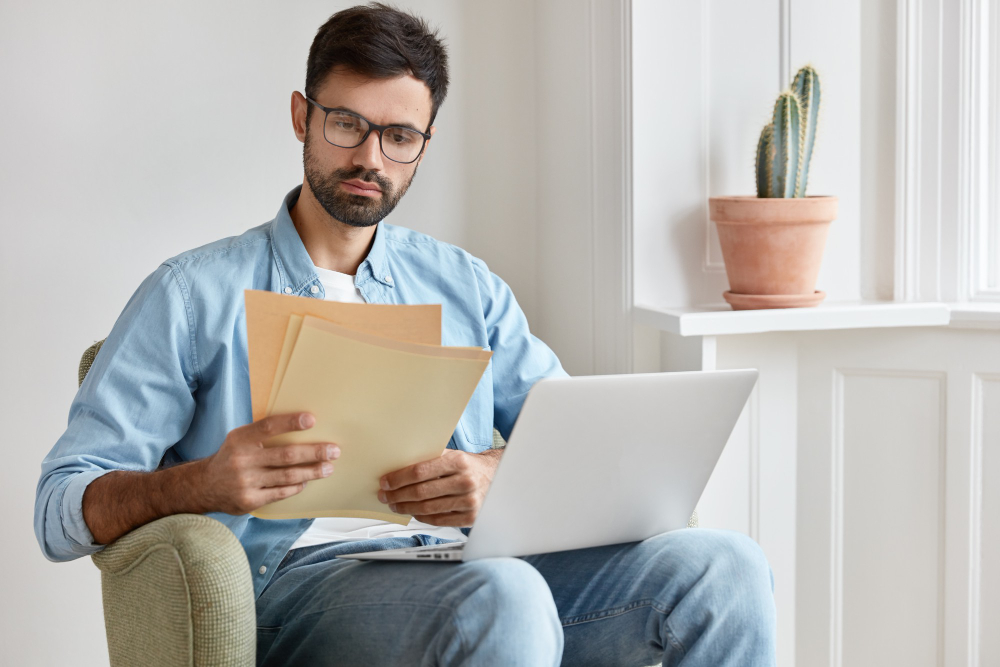 A professional man in a blue shirt reviewing patent documents next to text outlining steps for patent valuation and licensing preparation.