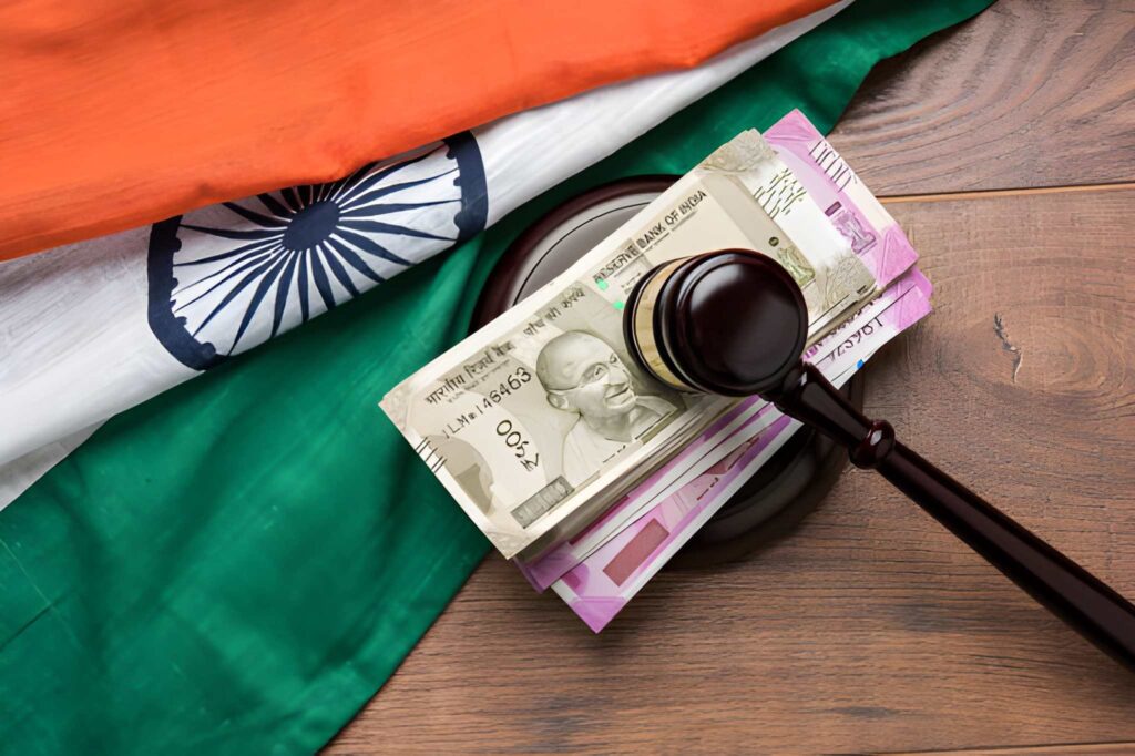 A gavel resting on Indian Rupee notes and the Indian national flag, illustrating patent filing fees and legal costs in India.