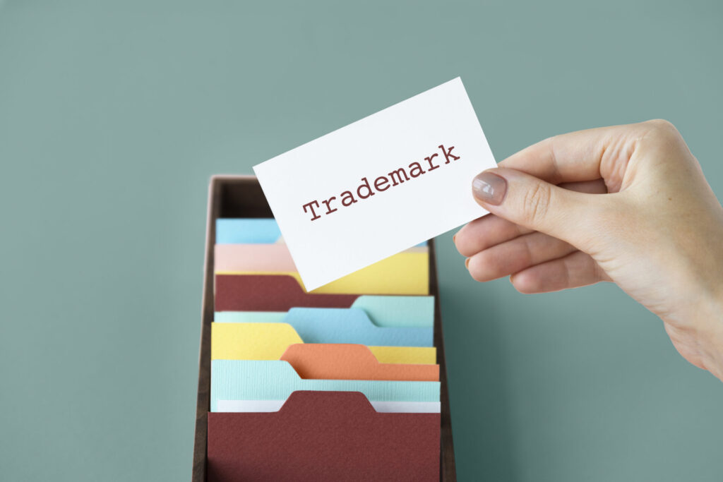 Hand holding a trademark card; a guide on why to hire a trademark lawyer in India versus DIY registration.