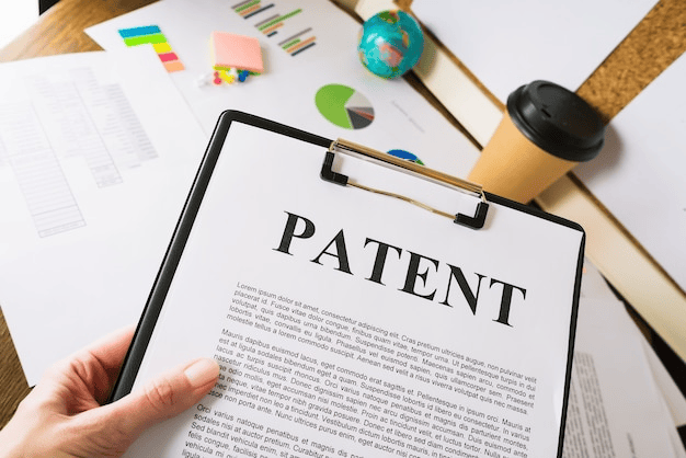 Person holding a clipboard with a "PATENT" document on an office desk.