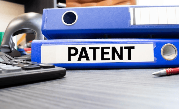 A blue office folder labeled PATENT on a desk, illustrating the final stage of filing a complete patent in India.