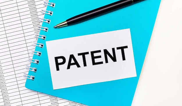 A blue spiral notebook with a pen and a white card reading "PATENT" next to a section of text about patent enforcement and protection strategies.