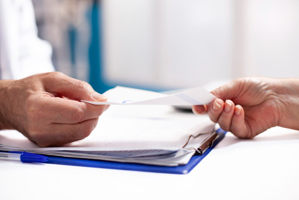 Person handing over patent transfer documents to another person, illustrating patent licensing and ownership transfer in India.