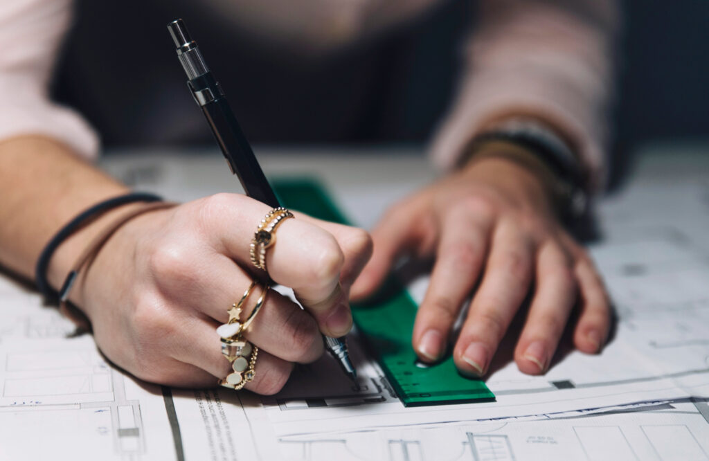 Hands using a ruler and pen for technical drafting next to text explaining patent application length and complexity requirements.