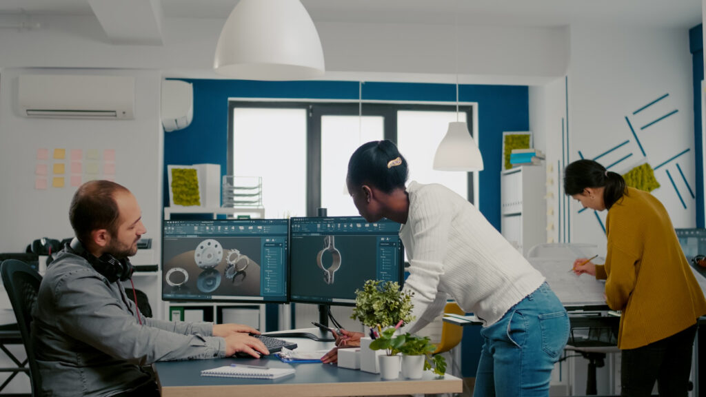 Professionals in a modern office designing 3D mechanical components on computer monitors, illustrating the concept of industrial design protection.
