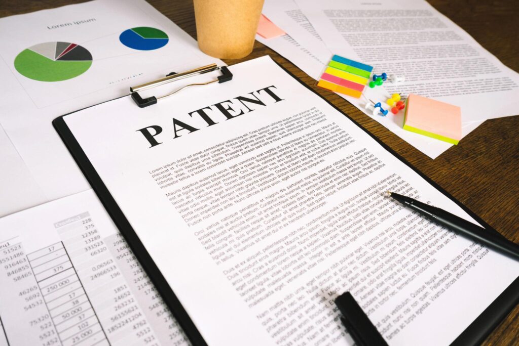 A clipboard featuring a legal document with the word PATENT printed at the top, placed next to business charts and legal paperwork explaining Section 60 of the Patents Act 1970 regarding the restoration of terminated patents.